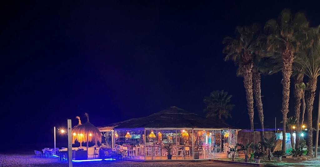 Terraza de Capay Beach Club iluminada de noche junto a la playa